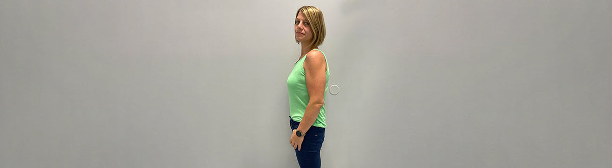 Sabrina (40) nach ihrer Gewichtsabnahme mit Precon im grünen Top, seitlich vor grauer Wand