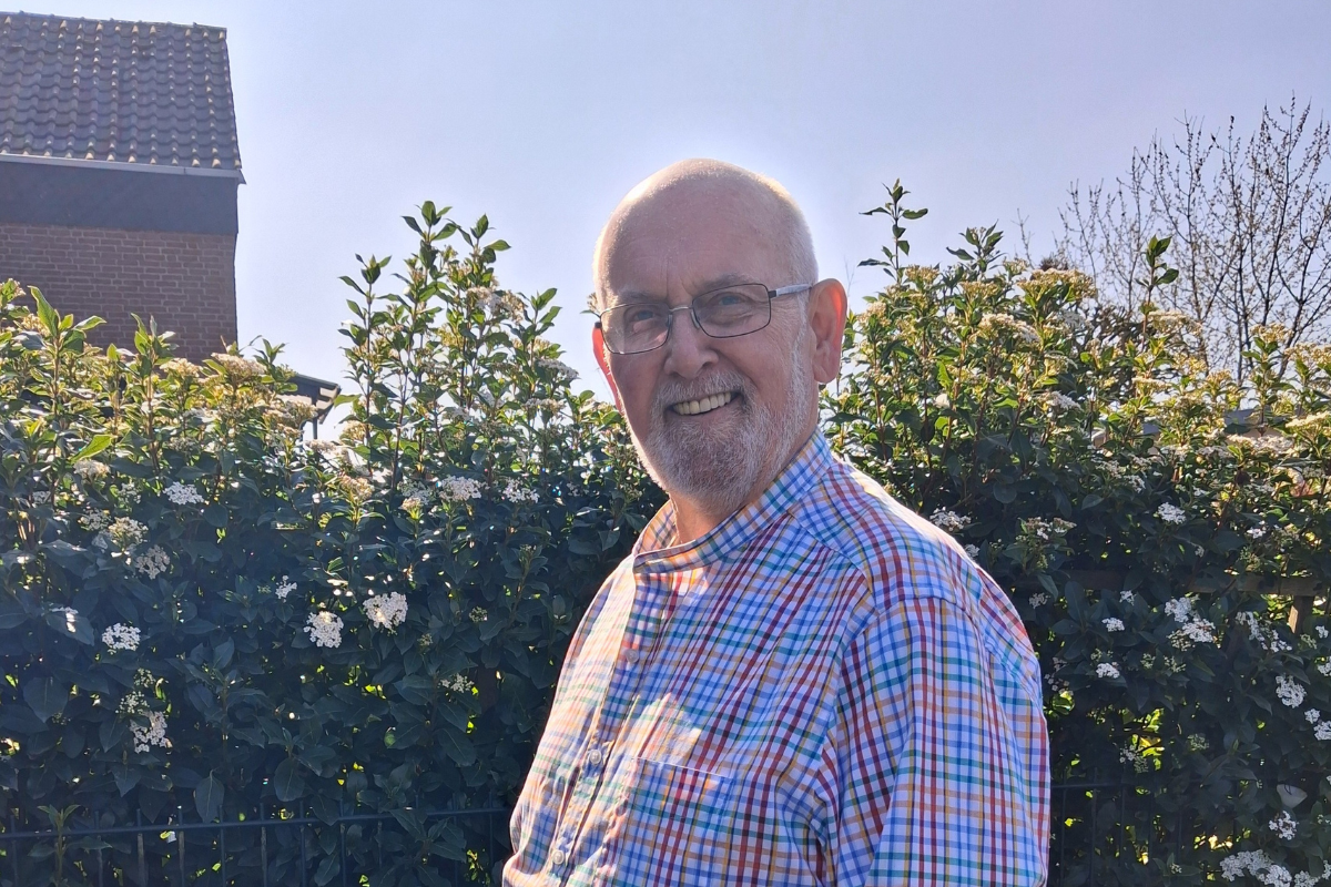 Wolfgang (70) im karierten Hemd lächelt vor einer blühenden Hecke – seine Erfahrung mit Precon