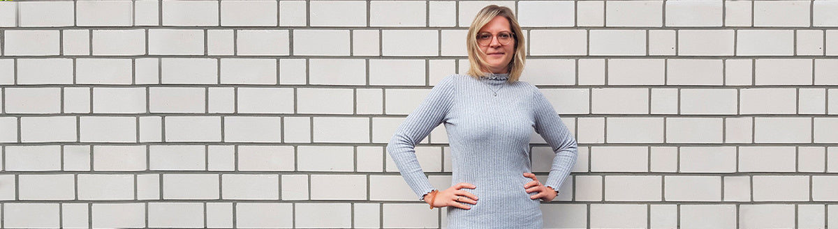 Mona-Jasmin (33) nach ihrer Gewichtsabnahme mit Precon im grauen Kleid vor einer weißen Ziegelwand