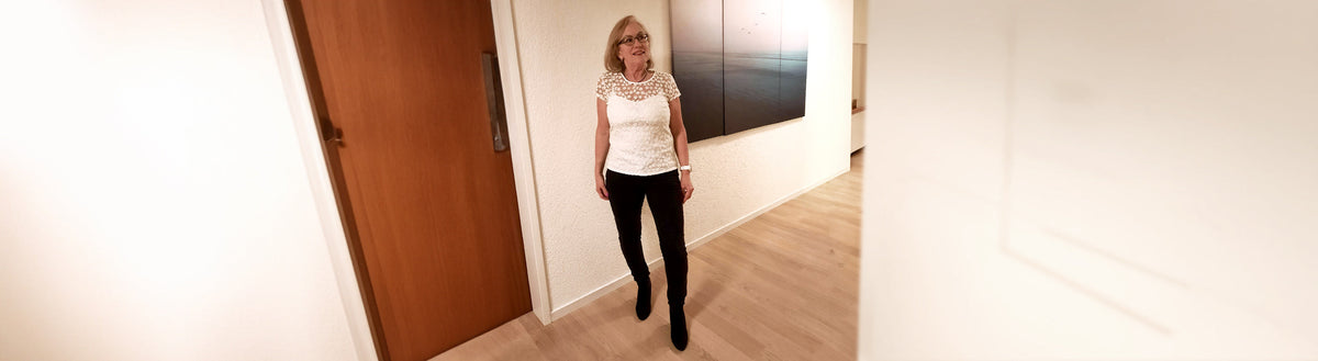 Erika (61) nach ihrer Gewichtsabnahme mit Precon, in weißem Shirt und schwarzer Hose im Flur