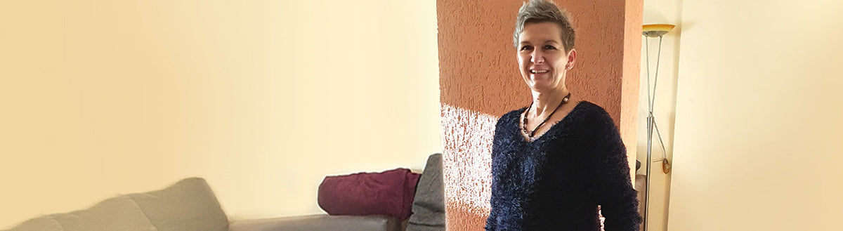 Anja (54) nach ihrer Gewichtsabnahme mit Precon, lächelnd in ihrem Wohnzimmer