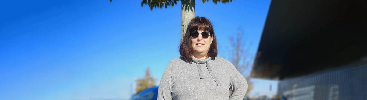 Uta (55) nach ihrer Gewichtsabnahme mit Precon, mit Sonnenbrille vor blauem Himmel